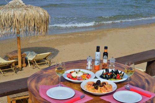 a table with plates of food and wine on the beach at Maria Beach Hotel in Kissamos