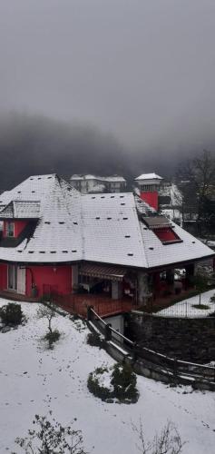 a large red house with snow on its roof at A casa di Lara in Beura