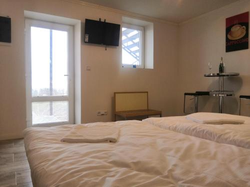 a large white bed in a room with two windows at Vehlovice Apartments in Mělník