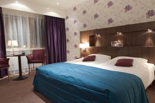 a hotel room with a large bed and a desk at Hotel Het Landhuis in Oldenzaal