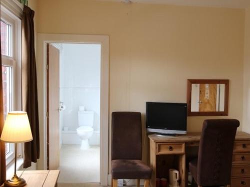 a room with a desk with a computer and a mirror at Aberthaw House Hotel in Barry