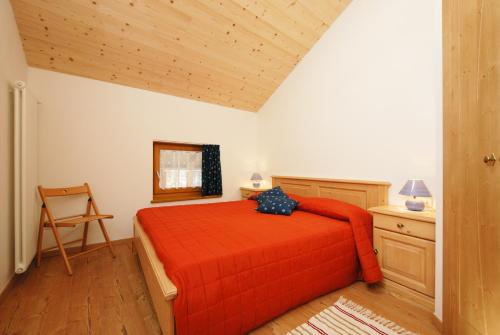 een slaapkamer met een rood bed en een stoel bij Casa Seler - Appartamento verde in Predazzo