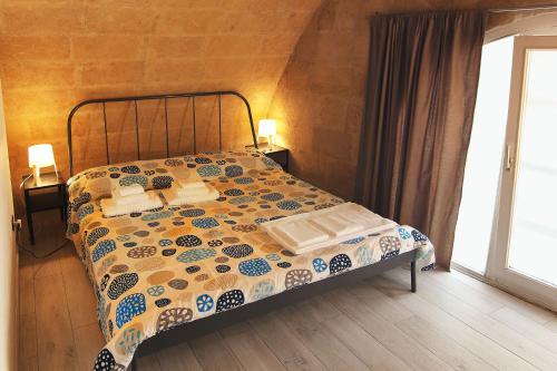 a bedroom with a bed with a quilt on it at Ostello dei Sassi - Matera Hostels in Matera