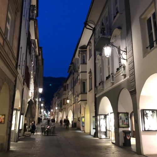 an empty street at night with people walking down the street at City Apartments Portico in Merano