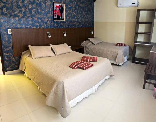 a bedroom with two beds with red pillows on them at Hotel Mitru in Tupiza