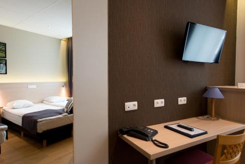 a hotel room with a bed and a desk with a phone at Hôtel de l'Univers Liège in Liège