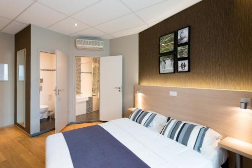 a bedroom with a large bed and a bathroom at Hôtel de l'Univers Liège in Liège