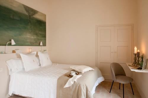 a bedroom with a white bed with a desk and a chair at Arkhé Hotel Boutique Pals in Pals
