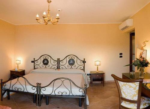 a bedroom with a bed and two chairs and a chandelier at Agostiniana Hotel in Forza dʼAgro