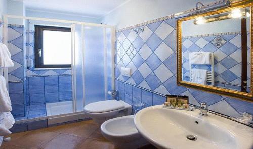 a bathroom with a sink and a toilet and a mirror at Agostiniana Hotel in Forza dʼAgro