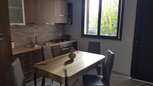 uma cozinha com uma mesa de madeira com cadeiras e um lavatório em Casa Vacanza Tony em Calatabiano