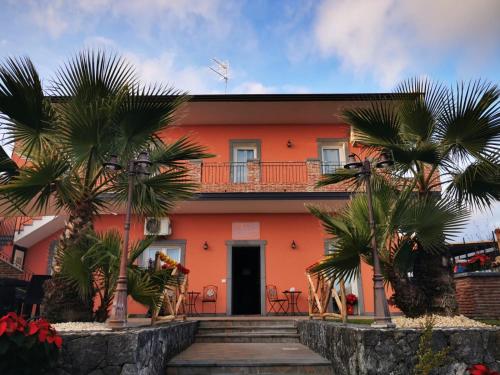 una casa arancione con palme di fronte di Martina Paradise Affitta Camere a Nicolosi