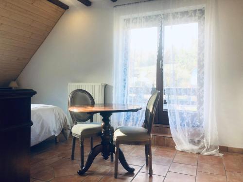 a table and two chairs in a room with a window at La Maison d'Ange in Le Hohwald