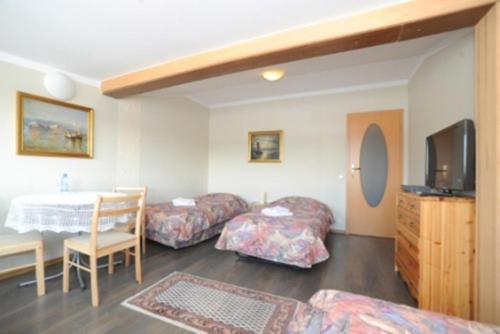 a room with three beds and a table and a tv at Galeria Pępowo in Żukowo