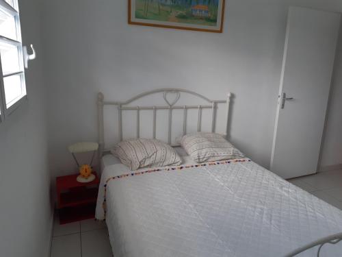 uma cama branca com duas almofadas num quarto em Chez JUJU em Le Gosier