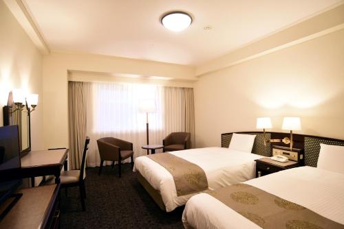 福島市にあるホテルサンキョウ福島のベッド2台とデスクが備わるホテルルームです。