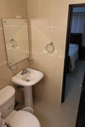 a bathroom with a sink and a toilet and a mirror at Tu Segundo Hogar en Santiago, La Cuidad CORAZÓN in Santiago de los Caballeros