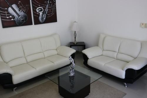 a living room with two white couches and a glass table at Tu Segundo Hogar en Santiago, La Cuidad CORAZÓN in Santiago de los Caballeros