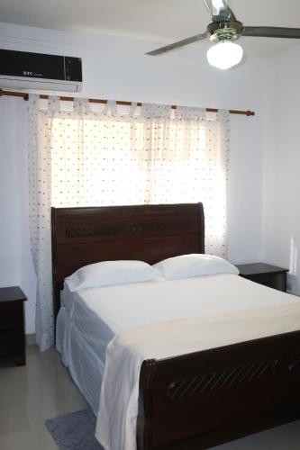 a bedroom with a large bed with white sheets at Tu Segundo Hogar en Santiago, La Cuidad CORAZÓN in Santiago de los Caballeros