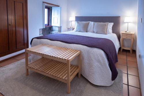 una camera con un grande letto e un tavolo in legno di Portas da Villa a Miranda do Douro