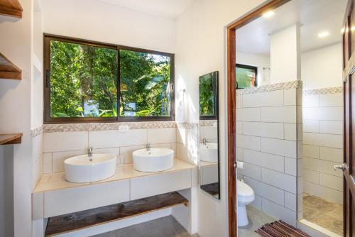 2 lavabos en un baño con ventana en Jungle Lodge at Wild Sun Rescue Center en Cabuya