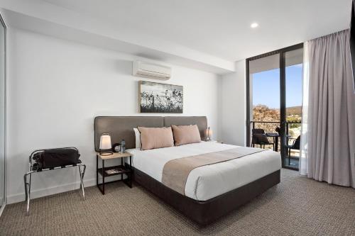 a bedroom with a large bed and a balcony at Quest Goulburn in Goulburn
