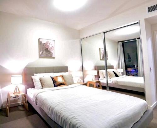 a bedroom with a large bed and a mirror at Lucid Apartment South Brisbane in Brisbane