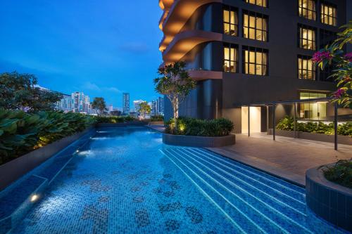 新加坡Citadines Rochor Singapore的夜晚建筑物前的游泳池
