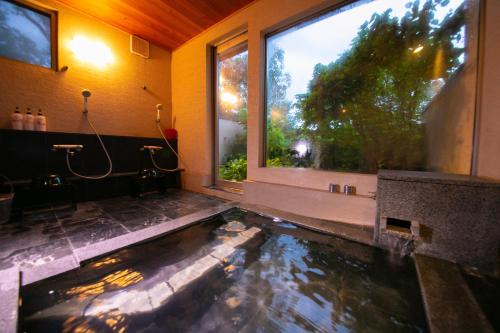 un bagno con laghetto al centro di una stanza di Innter Hill Tsubasa Yufuin a Yufu