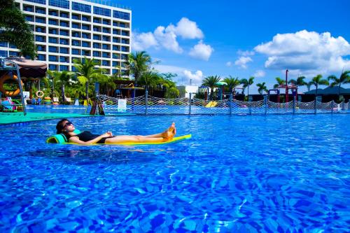 a woman and a dog on a surfboard in the water at Harman Resort Hotel Sanya in Sanya
