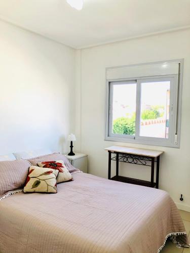 a white bedroom with a bed and a window at Apart de la Bahía con cochera in Bahía Blanca