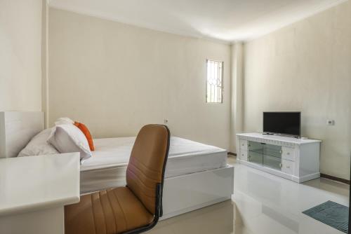 - une chambre avec un lit et un bureau avec une télévision dans l'établissement KoolKost Syariah near Kaza Mall Surabaya, à Surabaya