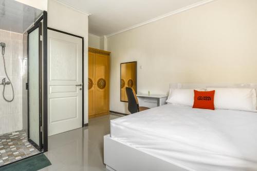 ein Schlafzimmer mit einem weißen Bett und einer Dusche in der Unterkunft KoolKost Syariah near Kaza Mall Surabaya in Surabaya