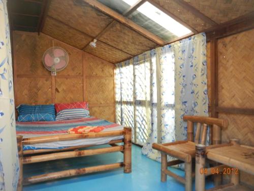 ein Schlafzimmer mit einem Bett und einem Stuhl in einem Zimmer in der Unterkunft Coron Backpacker Guesthouse in Coron