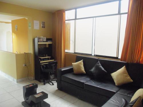 a living room with a black couch and a large window at Hostal Boulevard in Nazca