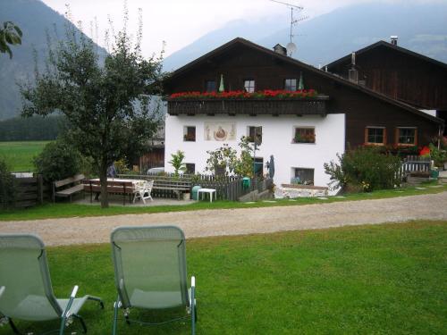 a house with a table and chairs in the grass at Lahnerhof in Campo Tures
