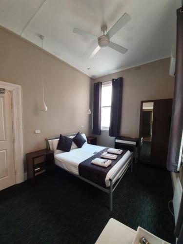 a hotel room with a bed and a ceiling fan at Grand Hotel in Newcastle