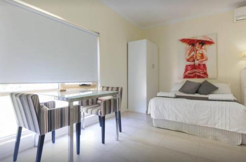 a bedroom with a bed and a table and a painting at M102 West Perth Studio Apartment near Kings Park in Perth