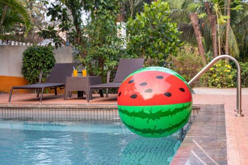 a large ball in the water near a swimming pool at Nature's Abode - The Wooden Villa at Morjim by StayVista in Morjim