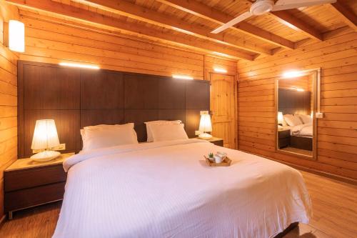 a bedroom with a large white bed and a mirror at Nature's Abode - The Wooden Villa at Morjim by StayVista in Morjim