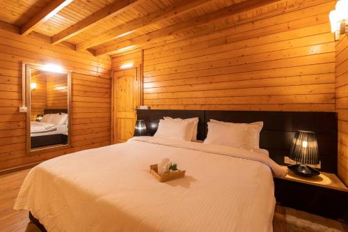 a bedroom with a large white bed with a mirror at Nature's Abode - The Wooden Villa at Morjim by StayVista in Morjim