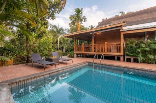 a swimming pool in front of a villa at Nature's Abode - The Wooden Villa at Morjim by StayVista in Morjim