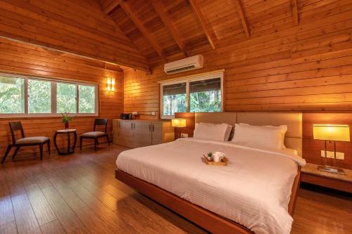 ein Schlafzimmer mit einem Bett in einer Holzhütte in der Unterkunft Nature's Abode - The Wooden Villa at Morjim by StayVista in Morjim