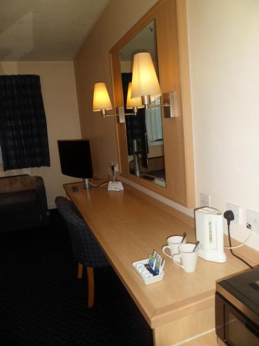 a desk in a hotel room with a mirror at Metro Inns Huddersfield in Huddersfield