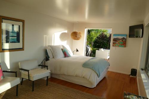 a bedroom with a bed and a chair and a window at Waterfront Bliss in Nelson