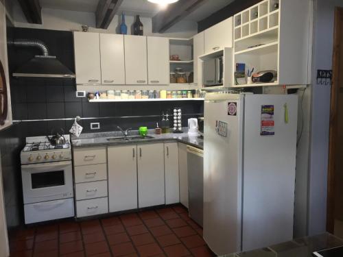 cocina con armarios blancos y refrigerador blanca en Casa Mora en San Martín de los Andes