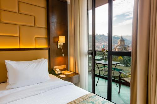 a hotel room with a bed and a balcony at KMM Hotel in Tbilisi City