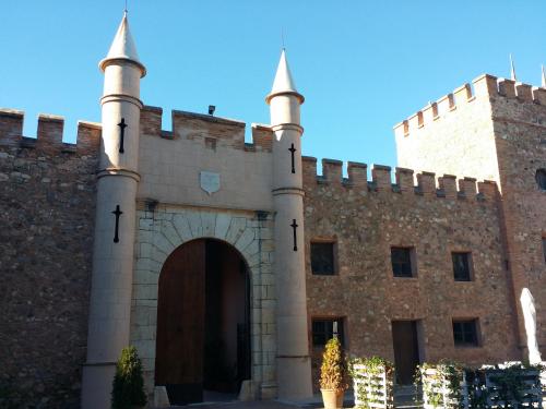 una entrada a un gran edificio de ladrillo con torretas en Masia de San Juan - castillo con piscina en plena Sierra Calderona, en Segorbe