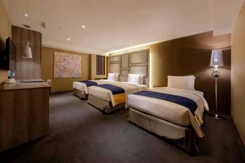 a hotel room with three beds and a desk at Green World ZhongXiao in Taipei