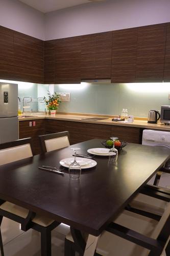 a kitchen with a black table and chairs in it at Trinidad Suites Johor, Trademark Collection by Wyndham in Nusajaya